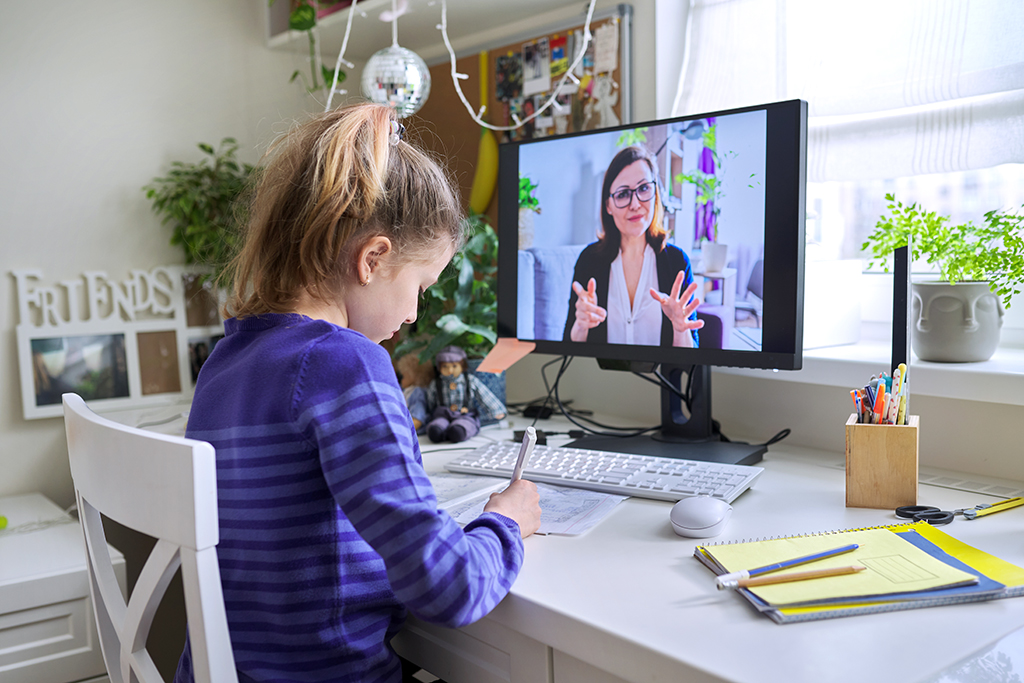 Tyttö opiskelee opettajan kanssa etänä tietokoneella videopuhelun avulla