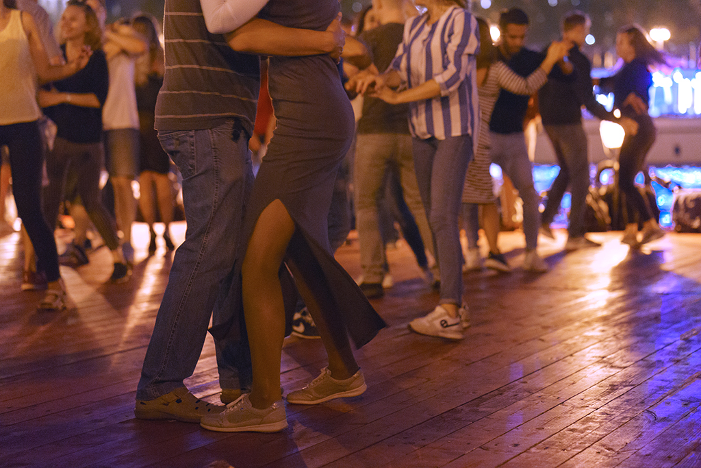 ihmisiä tanssimassa tanssilattialla, etualalla mies ja nainen tanssivat toisistaan kiinni pitäen