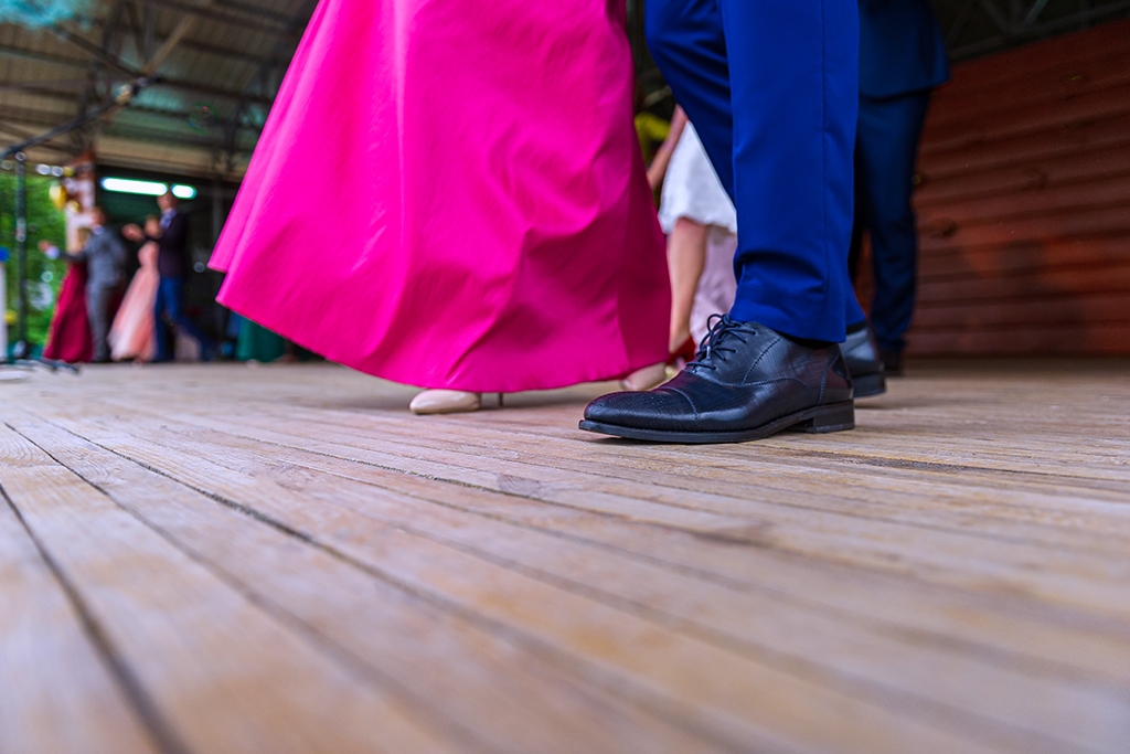 Legs of a dancing couple on the wooden floor of the outdoor dance floor.